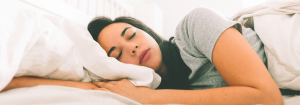 how to sleep better. A young woman asleep in bed.