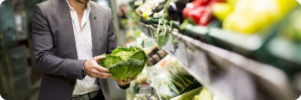 Man holding a cabbage in a supermarket to illustrate that choosing organic foods where possible can support your gut microbiome. 
