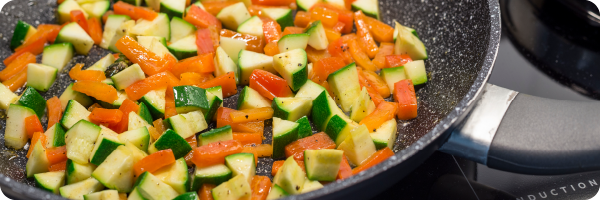Vegetables cooking in a pan on a hob to represent persistent organic pollutants that are often used in non-stick coating for cookware and can impact the gut microbiome. 
