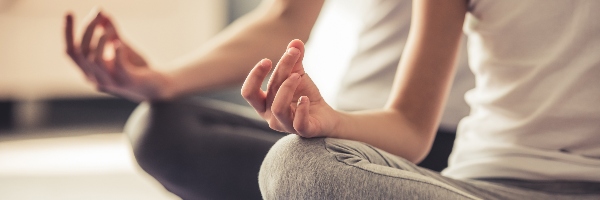Cropped image of young woman and her little daughter doing yoga together at home