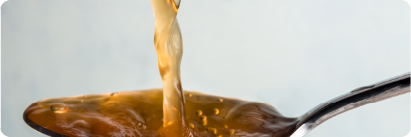 Apple cider vinegar pouring into a spoon.