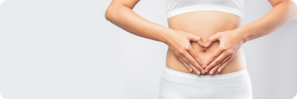 A person's abdomen with their hands in the shape of a heart framing their belly button. This image represents the gut and digestive health health indicators.