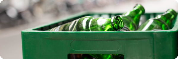 Empty green beer bottles in a green plastic recycling box showing that excess alcohol consumption can impact the gut microbiome. 