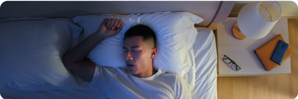 A young man lying in bad asleep with his mouth open mouth breathing during the night.