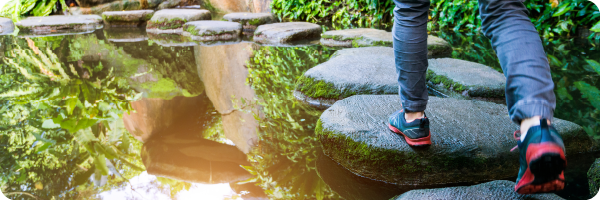 A person walking on stepping stones, representing that noticing your health indicators can be the stepping stones towards optimum health.