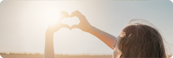 A person putting their hands in a heart shape in front of the vitamin producing sun.
