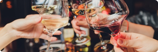 A group of friends clinking glasses of alcohol to celebrate.