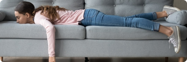 Woman in jeans and a pink top asleep on a couch