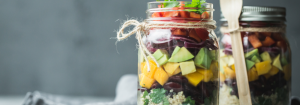 Two mason glass salad jars layered with colourful veg and fruit as one answer to the question how to eat more vegetables