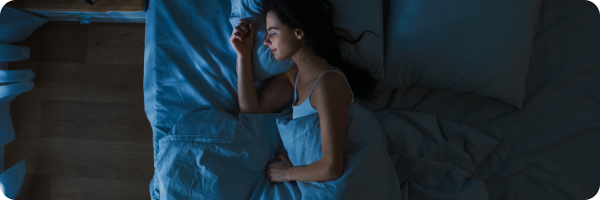 A person asleep in bed at night. 