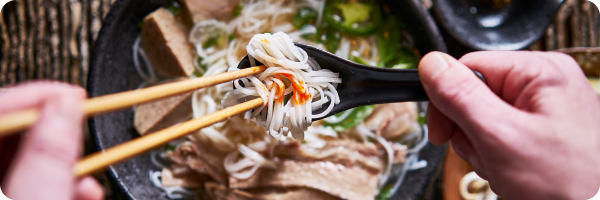 A person using chopsticks to eat a bowl of noodles.
