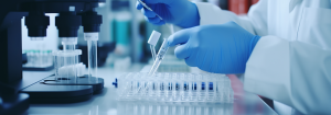 A close up of hands wearing blue latex gloves manipulating a test tube in a lab. Other lab equipment are on the surface.