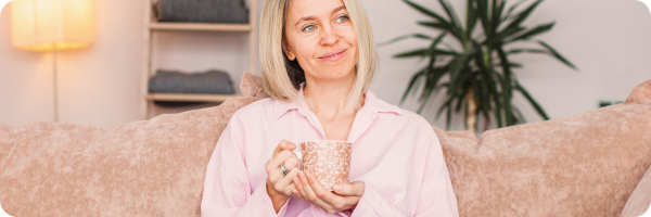 Woman relaxing at home with a warm drink, looking content and peaceful — representing the mental health benefits of quitting smoking.