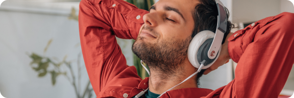 A man looking relaxed wearing headphones listening to music to represent how distraction techniques can help you stop smoking. 