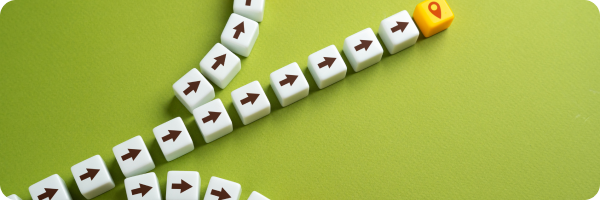 Rows of tiles against a green background with arrows pointing forwards going in different directions, with a location pin icon on one yellow tile at the end of one line of tiles to represent the importance of exploring different options when quitting smoking. 