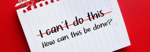 A piece of paper from a notebook against a red background with the words ' I can't do this' crossed out and the words 'How can this be done?' written underneath to represent how to become smoke free for good with nicotine replacement therapy.
